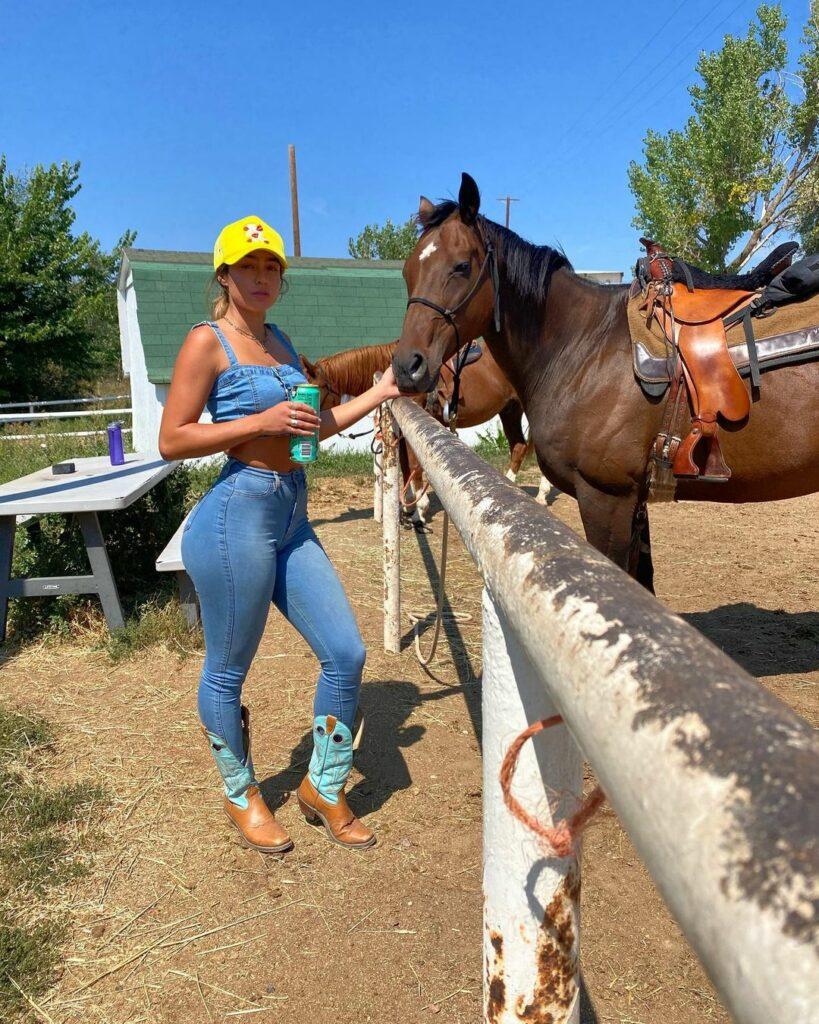 Sommer Ray posing next to a horse.