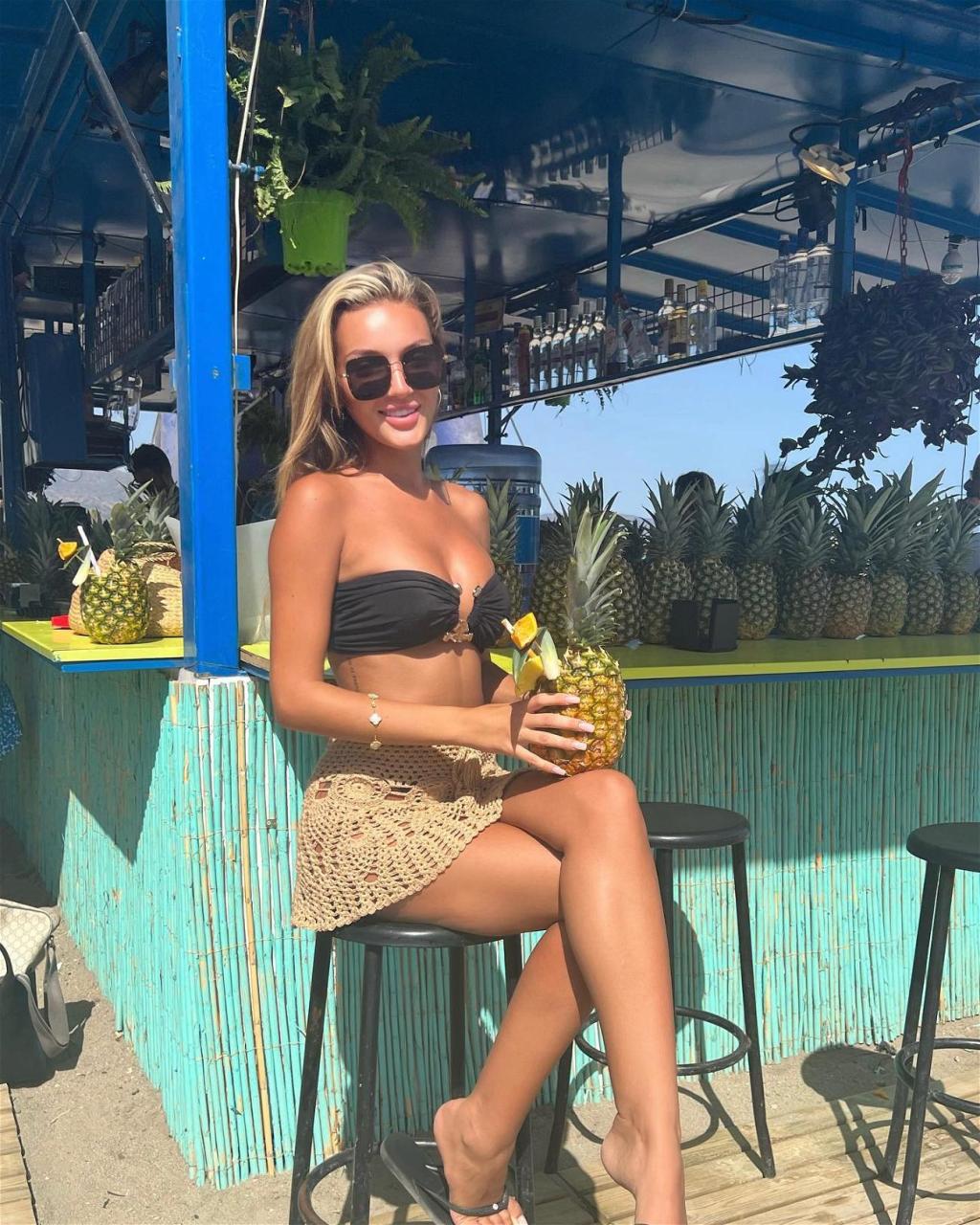 Beaux Raymond Sips From A Pineapple In A Strapless Black Bikini