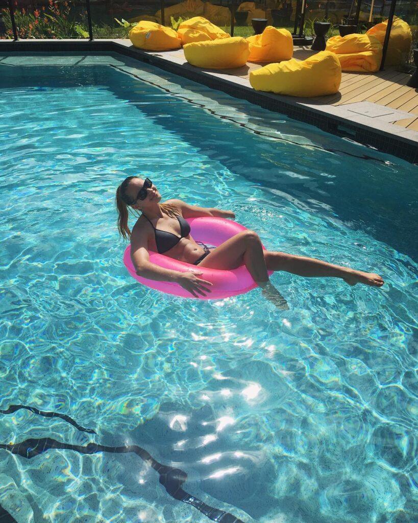 Shallon Olsen relaxing on the pool floatie while wearing a black bikini.