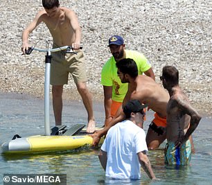 Help from the pros: Cruz climbed aboard his paddle board with a little help from the pros