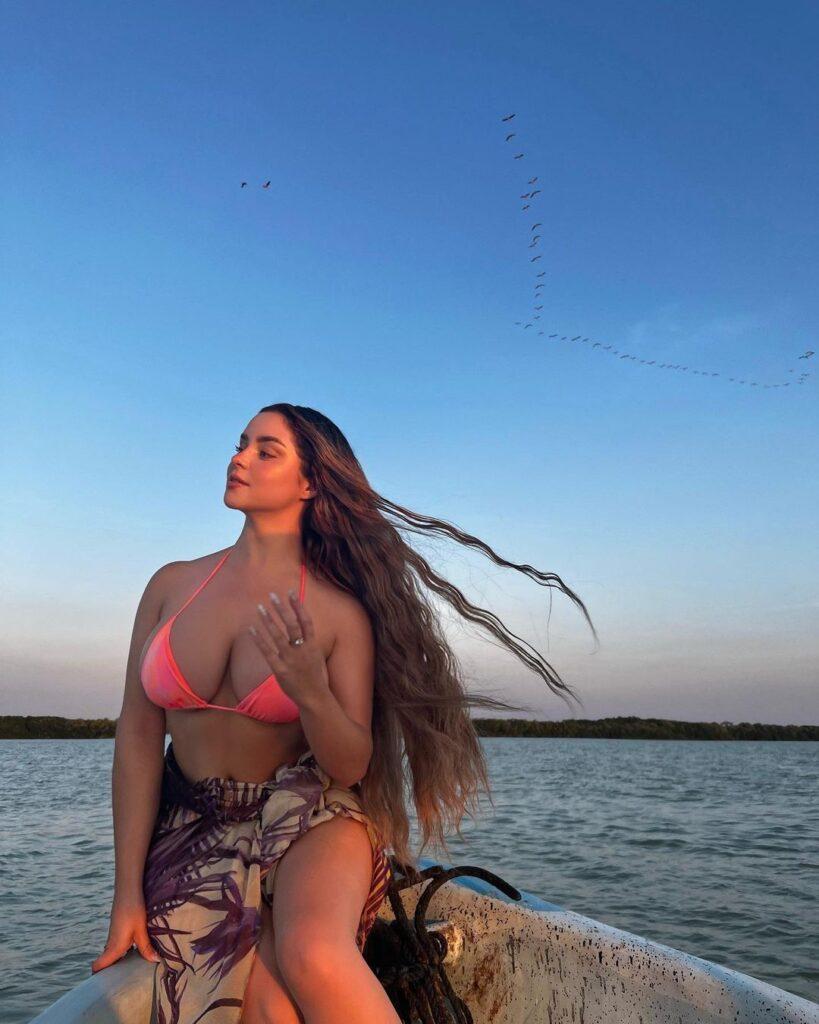 Demi Rose sitting on the edge of the boat.