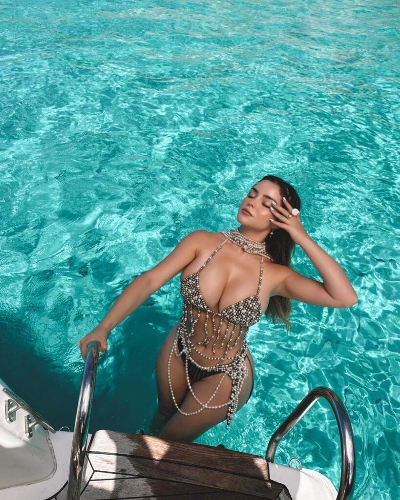 Demi Rose standing on the ladder of a boat.