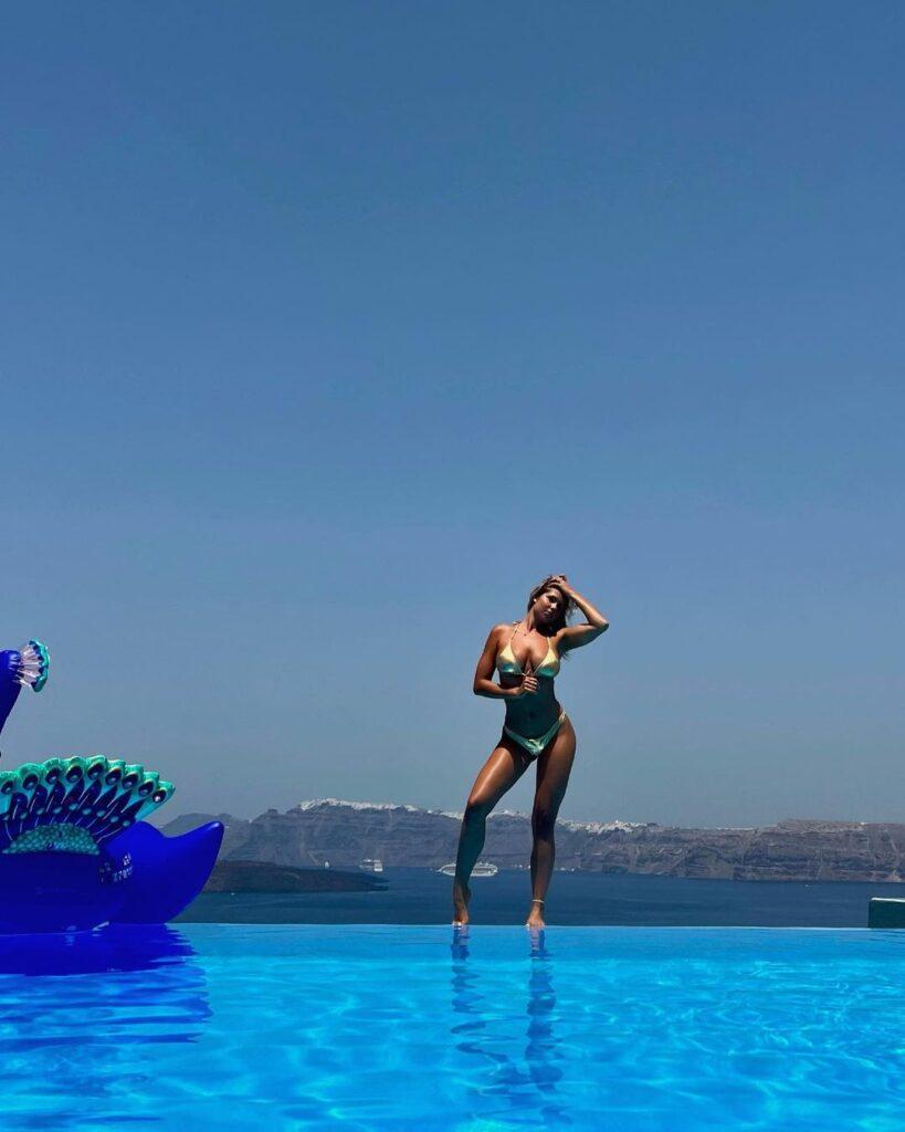 Andreea Dragoi poses on the ledge of the pool while rocking a gold bikini.