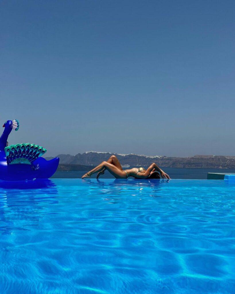 Andreea Dragoi lounges on the ledge of the pool while rocking a gold bikini.