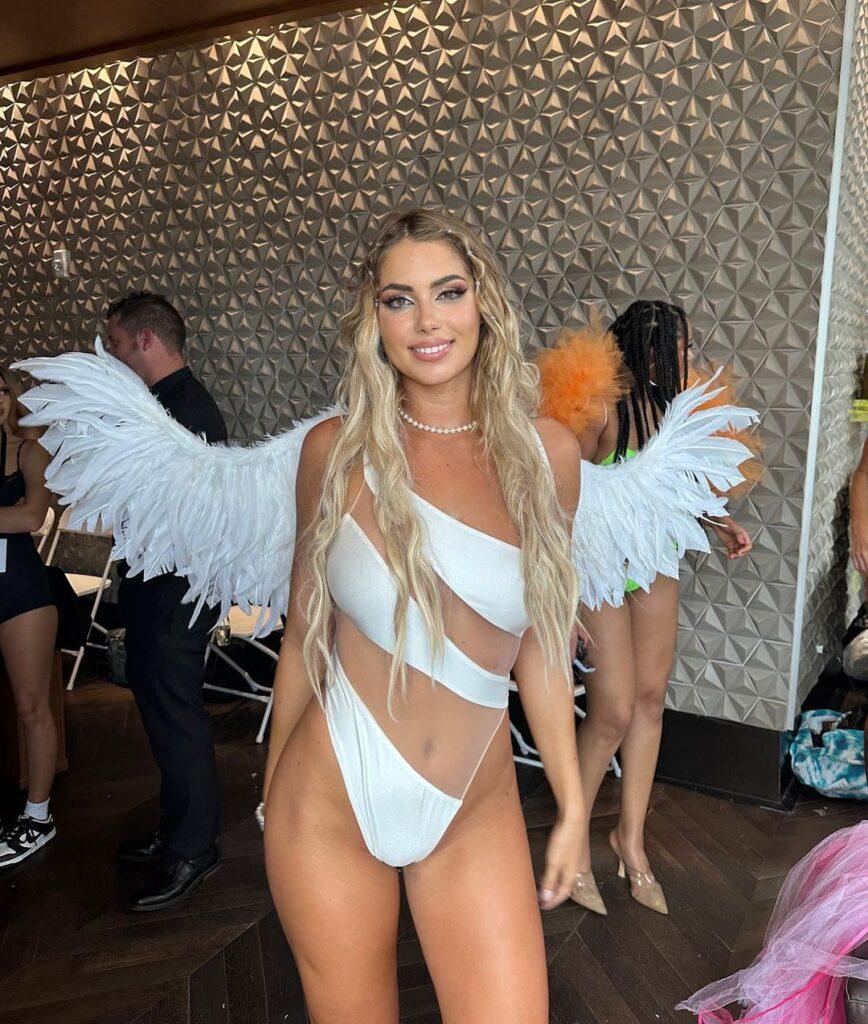 Andreea Dragoi posing for the camera in a white swimsuit and faux wings.