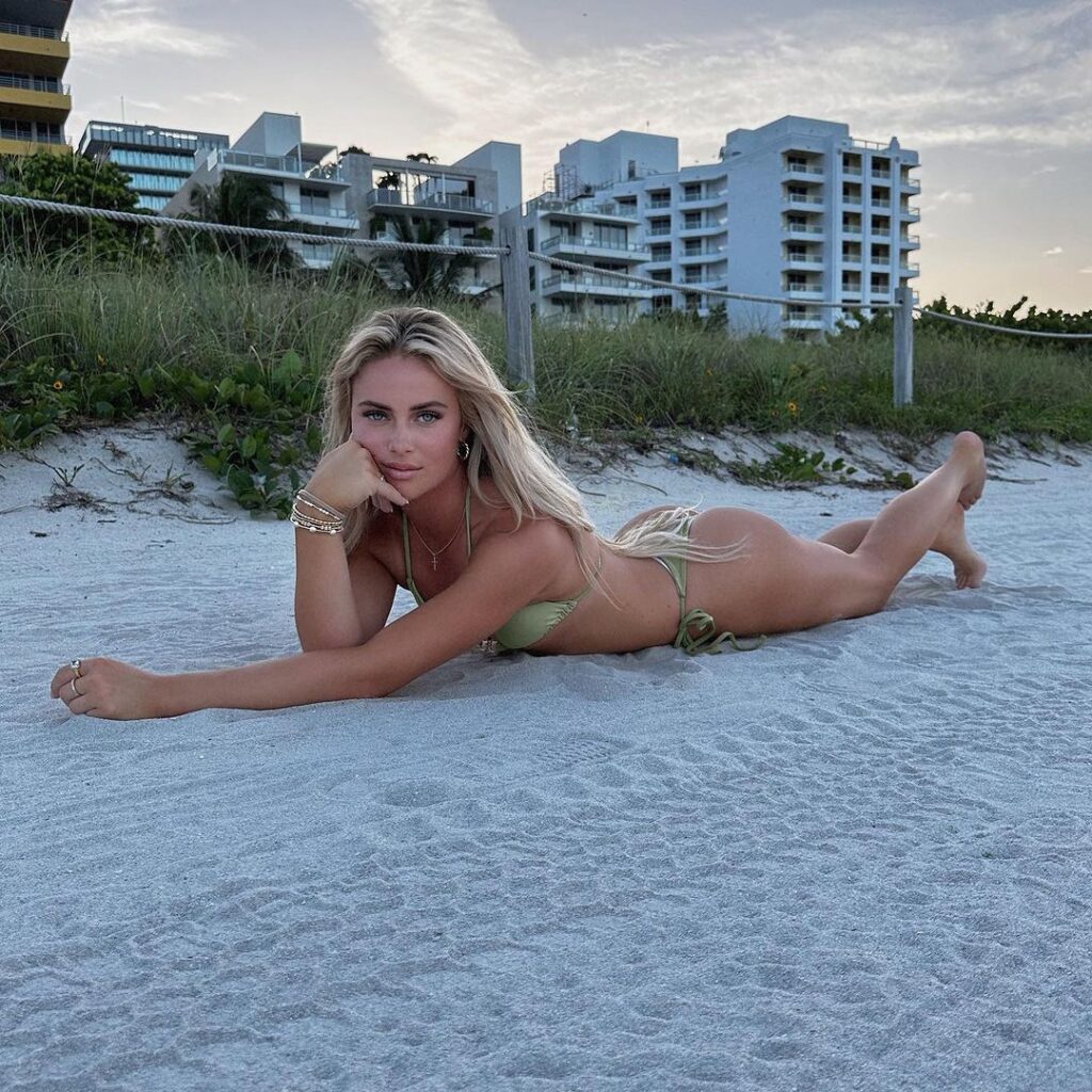 Brylie St. Clair wears a light green bikini while lounging on the sand.