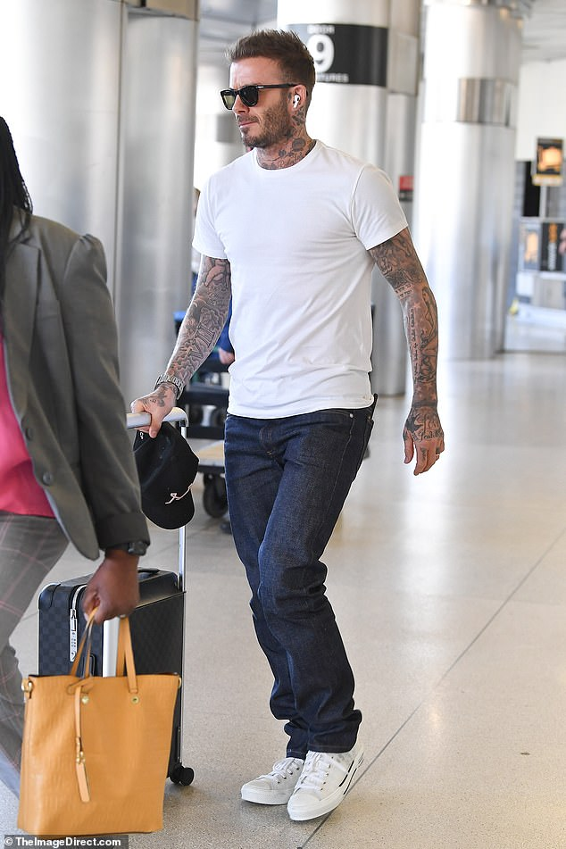 David Beckham displays his heavily-tatted arms as he arrives in Miami ...