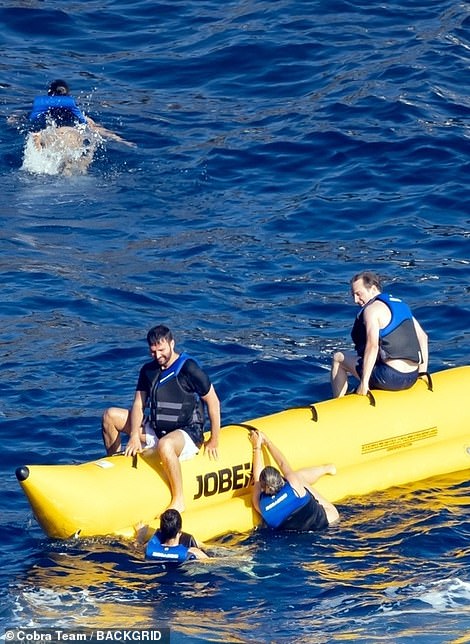 Clinging on: The group got soaked as they were thrown off the inflatable