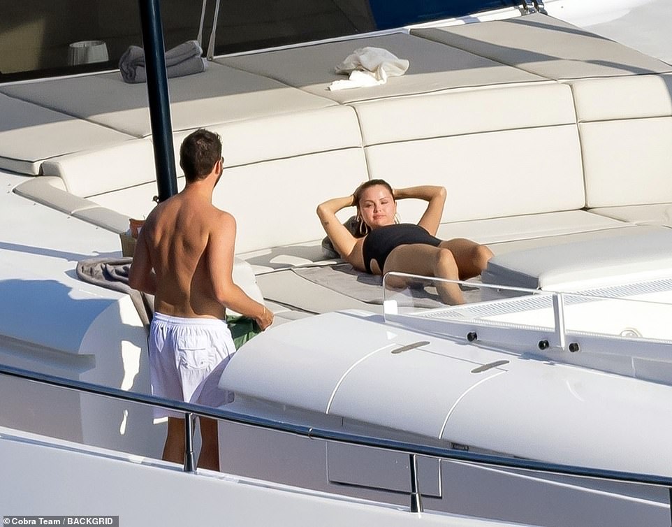 Chatting: Selena looked very relaxed as she lay back for a spot of sunbathing