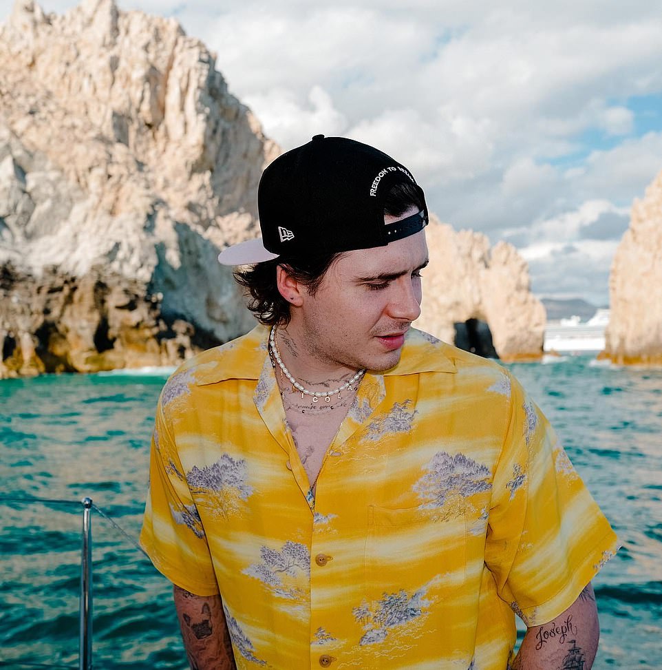 Picturesque views: The media personality slightly turned his head away from the camera with a stunning rock view in the water behind him