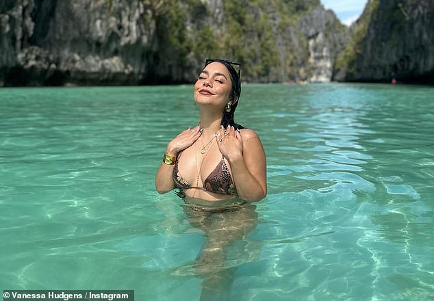 Soaking up the sun: The first photo was a snap of Hudgens standing in crystal clear blue water while tilting her head up towards the bright sunshine to strike a pose for the camera