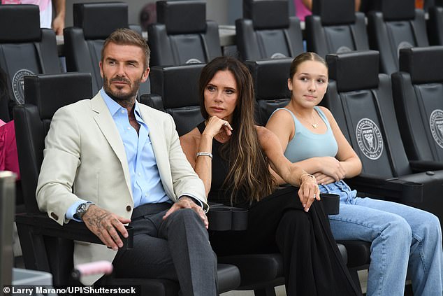 Three's company: The pair were joined by their youngest child, 12-year-old daughter Harper, who sat alongside them in the stands