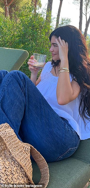 Cocktail Time: While laying down in the green cushioned lounge chair, Jenner held a cocktail glass with a yellow drink in her hands