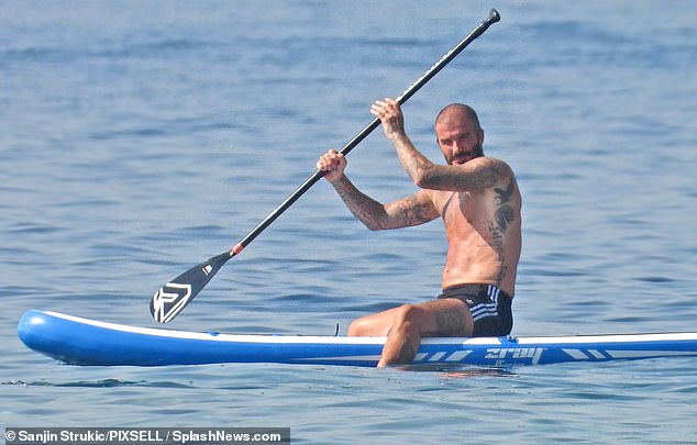 Toned: David showed off his muscular frame and tattooed chest as he went shirtless in black shorts while practicing his skills on a paddleboard