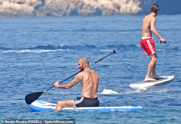 Having fun: David and Cruz took some time away from the yacht as they larked about on a paddleboard and a fliteboard - an electrically powered surfboard