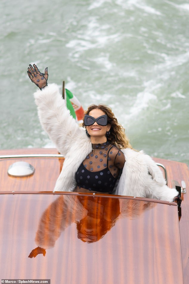 Stylish: She completed the glamorous ensemble with a white fur coat and platform heels, while accessorising with quirky sunglasses