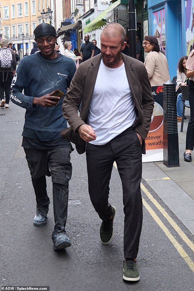 Smart casual: The global football star, 48, looked incredibly dapper as he strolled the streets of London wearing a brown button-up shirt, a white tee, and a pair of tailored trousers