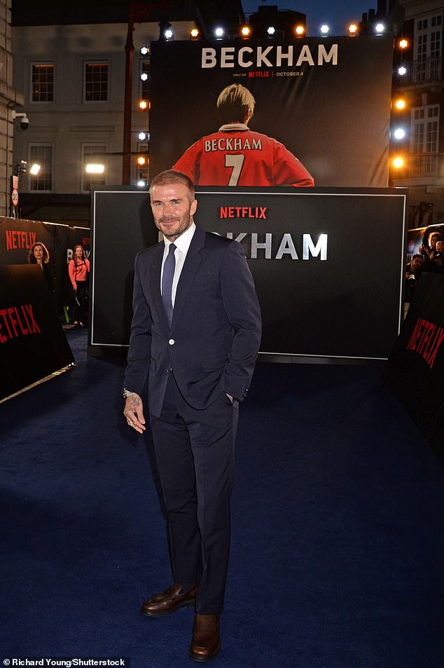 Iconic: David posed in front of a throwback snap of him in his number seven football shirt as he marked the release of his documentary