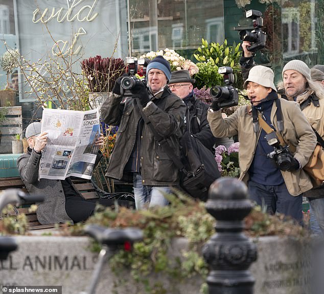 Look away please, nothing to see here: The former footballer hid behind his newspaper as a troop of photographers raced past 