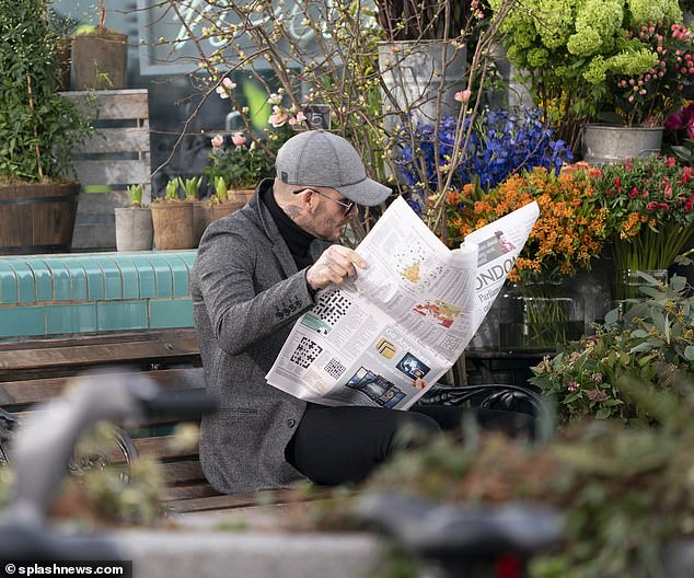 Don't mind me: The former Manchester United and England footballer pulled a baseball cap low over his head while hiding his instantly recognisable features behind a newspaper