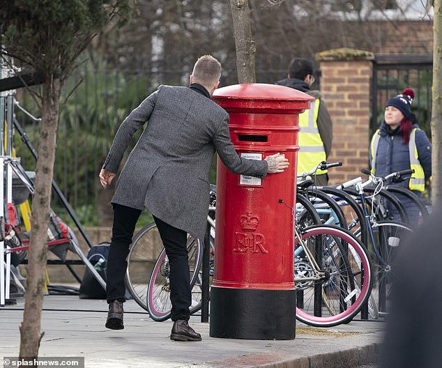 Here we go: Beckham was filmed slapping shipping labels on a  variety of very British objects on Tuesday 