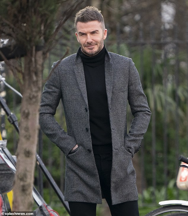 Smart: Beckham looked typically stylish in a monochrome coat and slim-fitting jeans