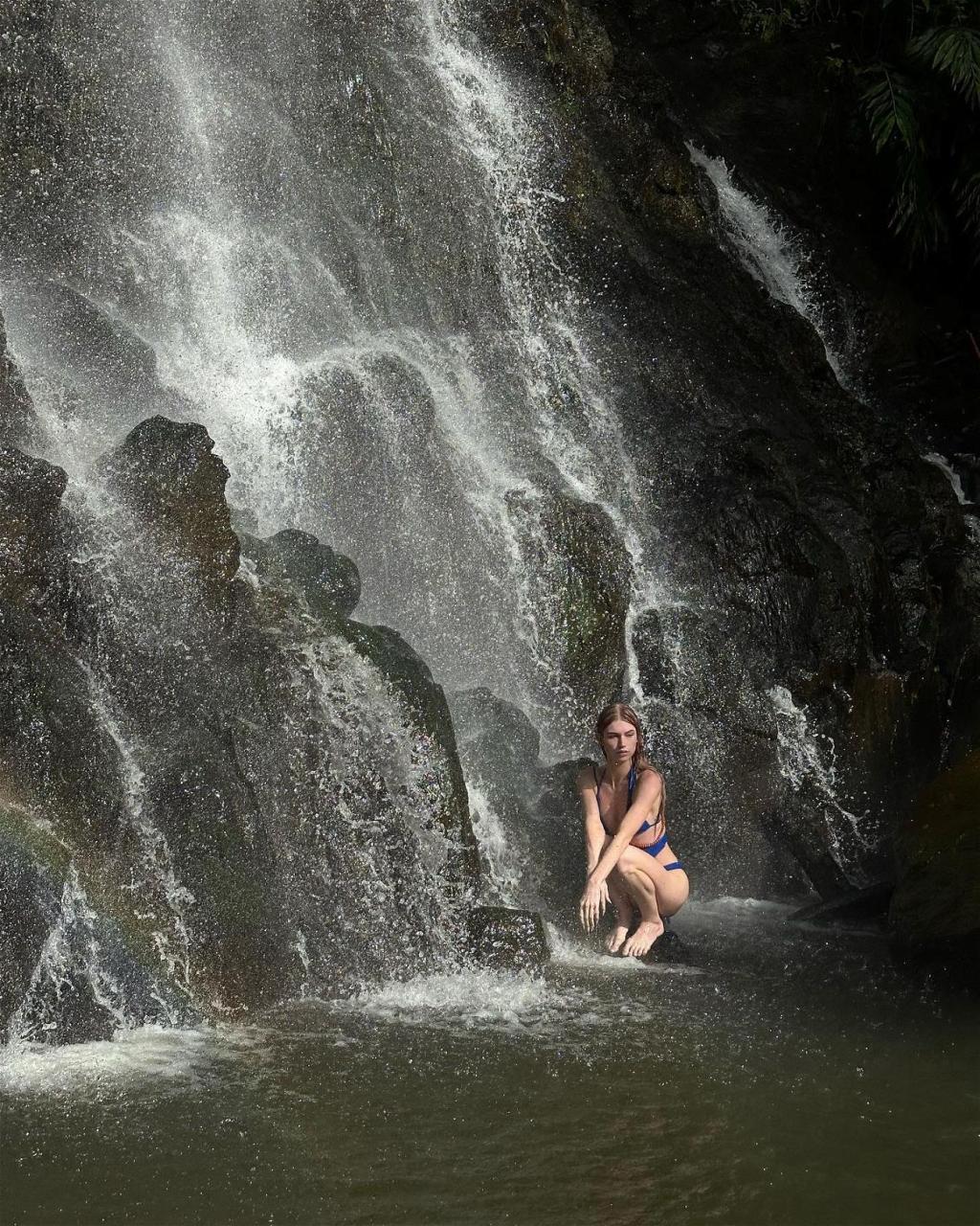 Brittan Byrd Steps Under A Waterfall In A Cut-Out Blue Swimsuit