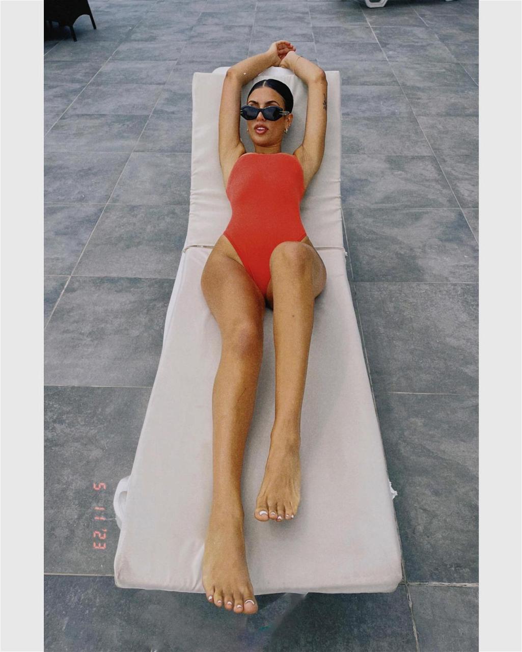 Emily Faye Miller sunbathes in a one-piece swimsuit