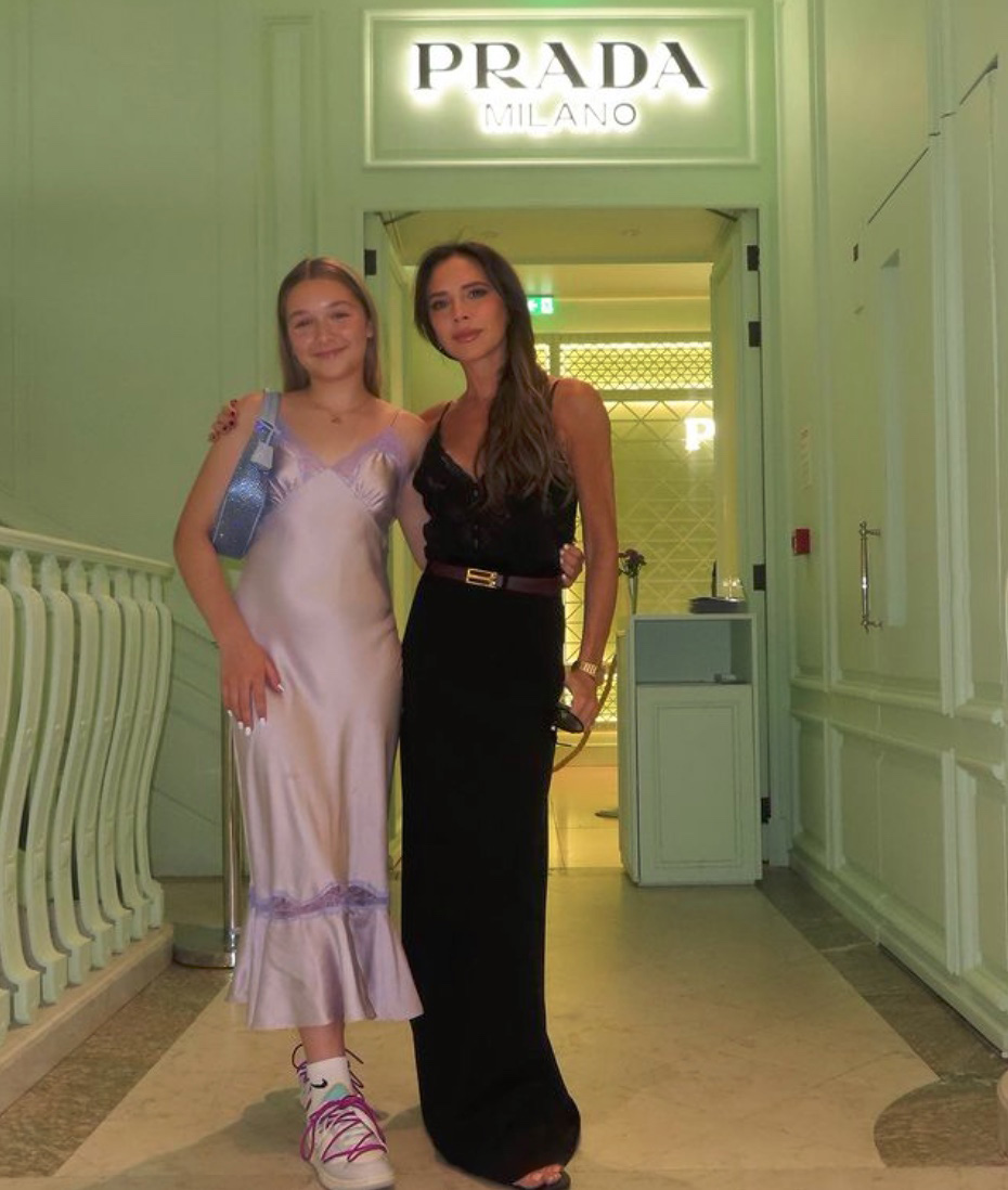 harper beckham and victoria beckham posing beneath a PRADA sign