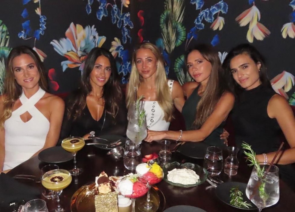 victoria beckham and four other women sitting at a restaurant table with cocktails and dessert